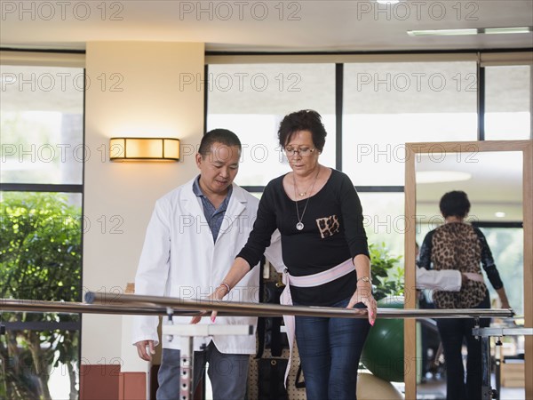 Physical therapist helping walking patient