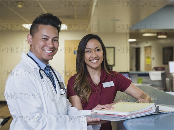 Portrait of smiling doctor and nurse with binder in hospital