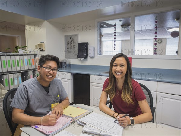 Portrait of smiling nurses writing in binders in hospital