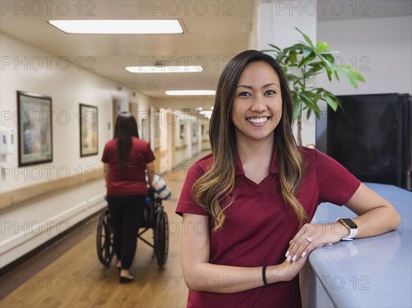 Portrait of smiling nurse leaning on counter in hospital