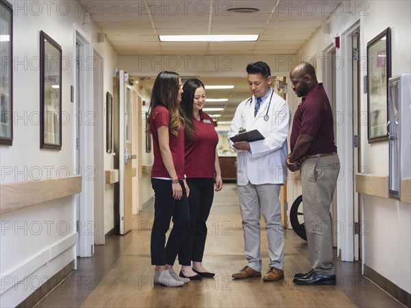 Doctor and nurses reading clipboard in hospital corridor