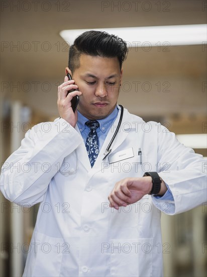 Filipino doctor talking on cell phone and checking the time