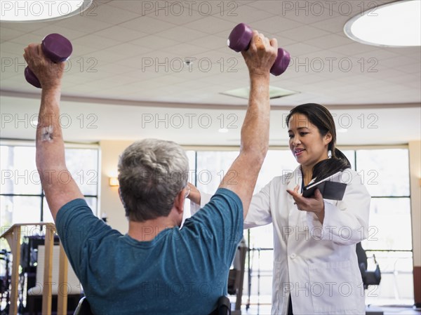 Physical therapist helping man lifting weights