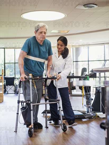 Physical therapist helping man using walker