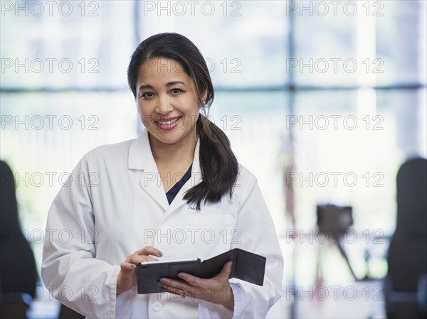 Portrait of smiling Asian physical therapist using digital tablet