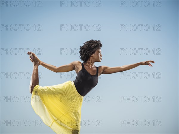 Black woman standing on one leg holding foot