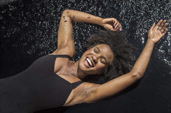 Laughing black woman laying in water