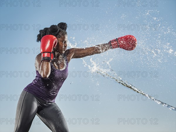 Water spraying on black woman boxing