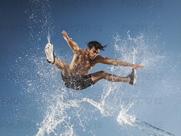 Water spraying on jumping Hispanic man