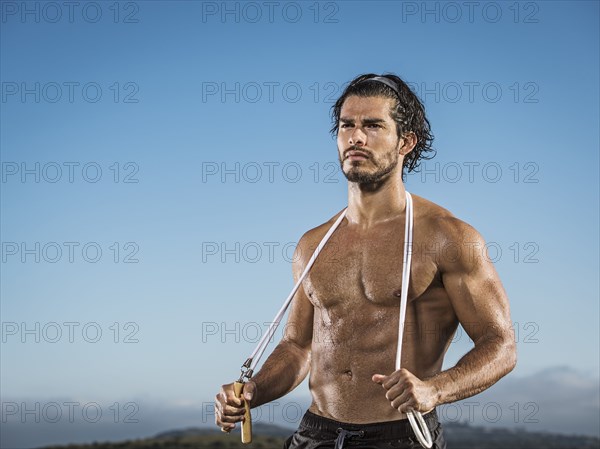 Confident Hispanic man holding jump rope