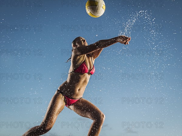 Water splashing on Caucasian woman playing volleyball