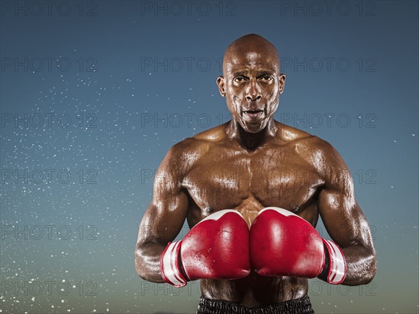 Water splashing on confident black boxer outdoors