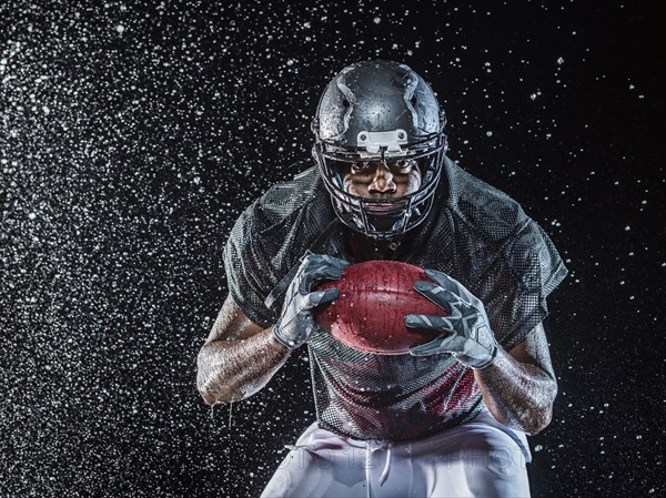 Water splashing on black football player