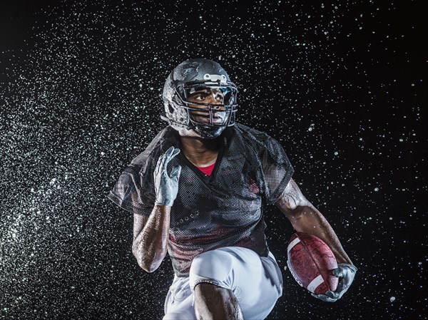 Water splashing on black football player running