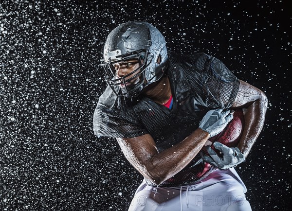 Water splashing on black football player