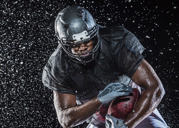 Water splashing on black football player