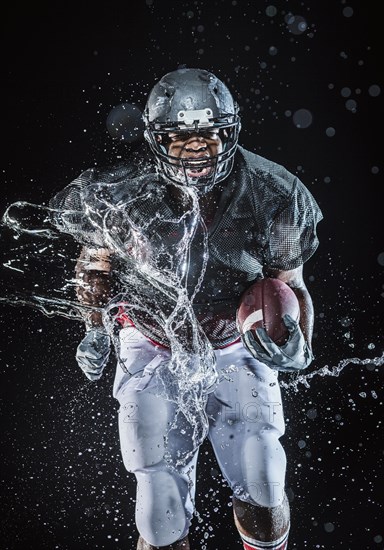 Water splashing on black football player running