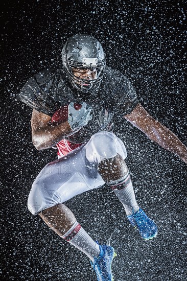 Water splashing on black football player jumping