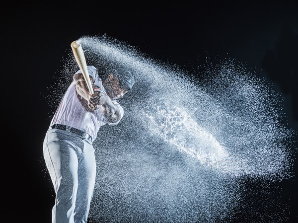 Water splashing from swinging bat of black baseball player