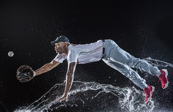 Water splashing on diving black baseball player