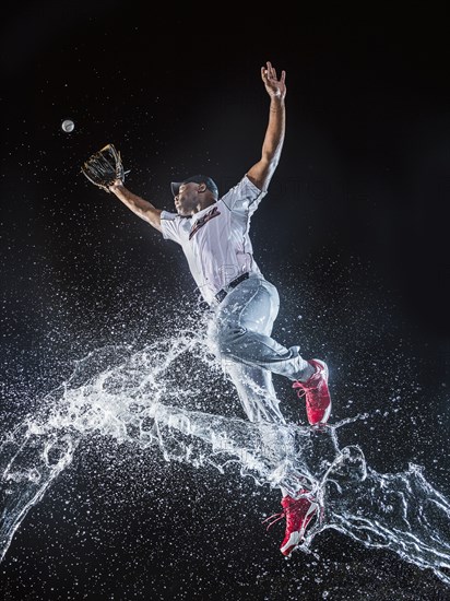 Water splashing on jumping black baseball player