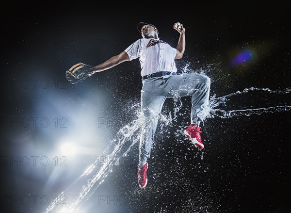 Water splashing on jumping black baseball player