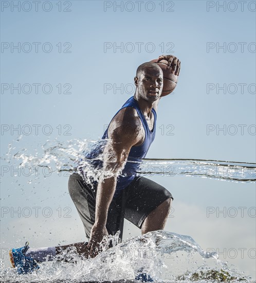 Water splashing on Black man dribbling basketball