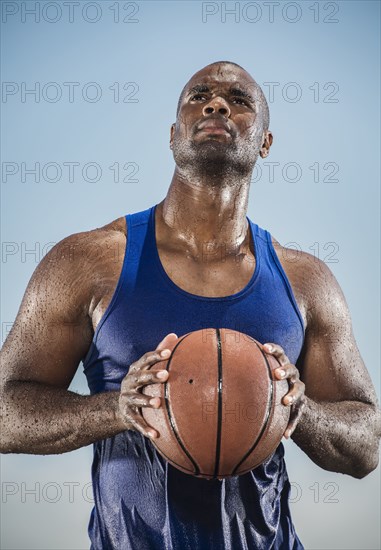 Pensive sweating Black man holding basketball