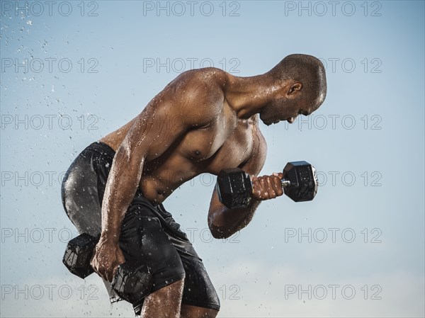 Water splashing on Black man lifting weights