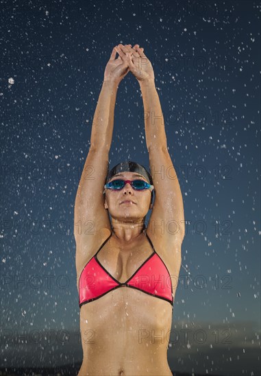 Water splashing on Caucasian swimmer stretching arms