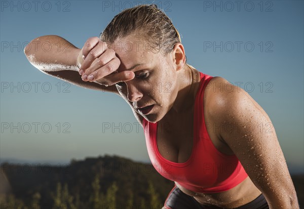 Caucasian woman wiping sweat from forehead
