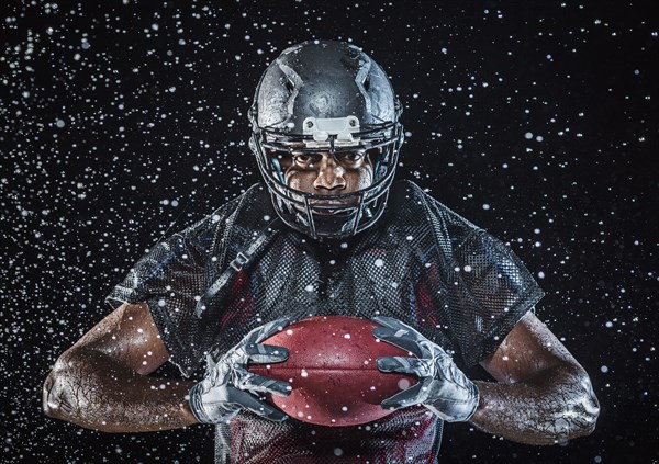 Water splashing on Black football player holding football