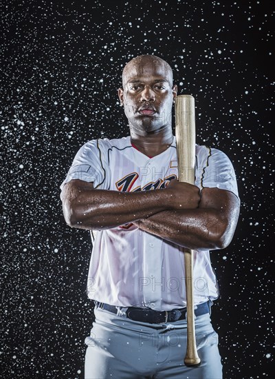 Water splashing on Black baseball player holding bat