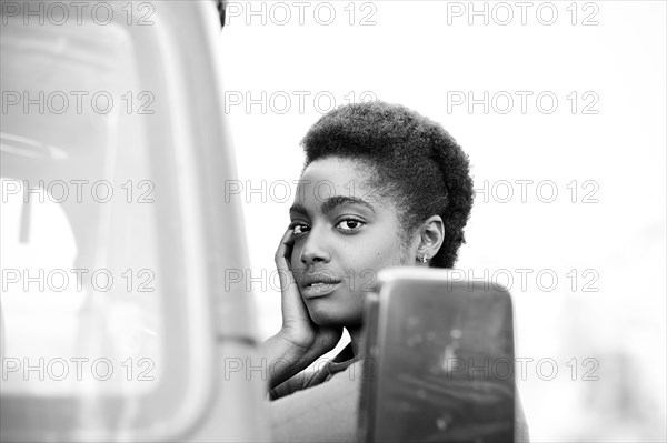 African American woman leaning on car