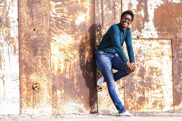 African American woman leaning on rusty metal wall