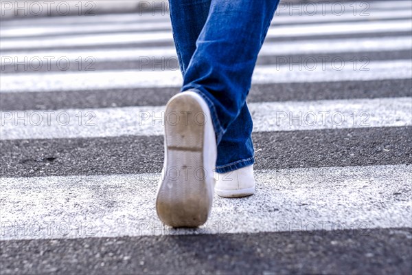 Legs of African American woman walking in crosswalk