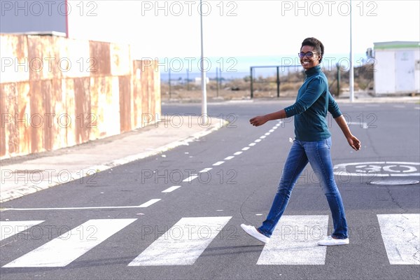 Smiling African American woman walking in crosswalk