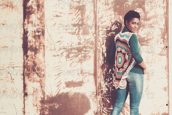 Smiling African American woman standing near rusty metal wall