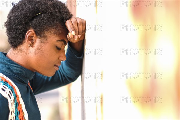 Pensive African American woman leaning on wall