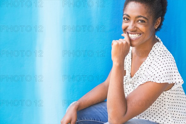African American woman smiling near blue wall