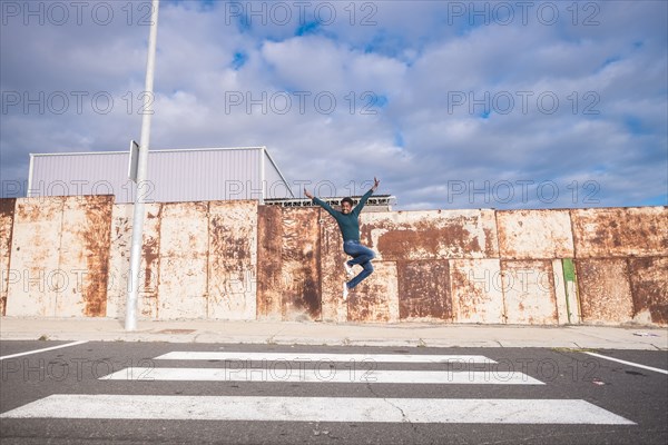 African American woman jumping for joy in crosswalk