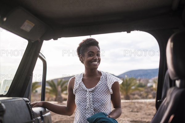 Smiling African American woman opening car door