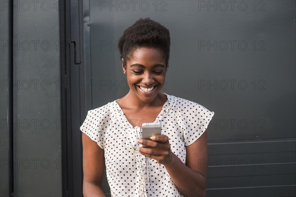 Smiling African American woman texting on cell phone