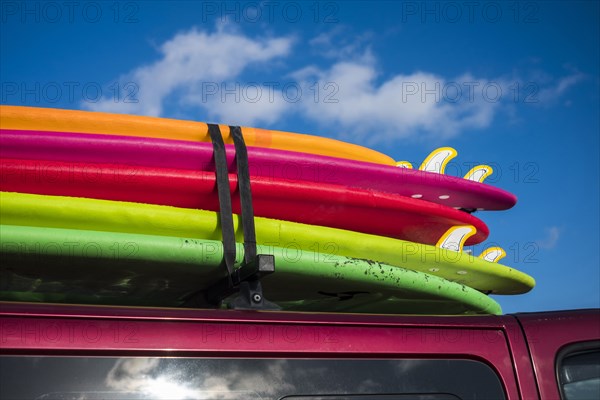 Multicolor surfboards strapped to roof of car