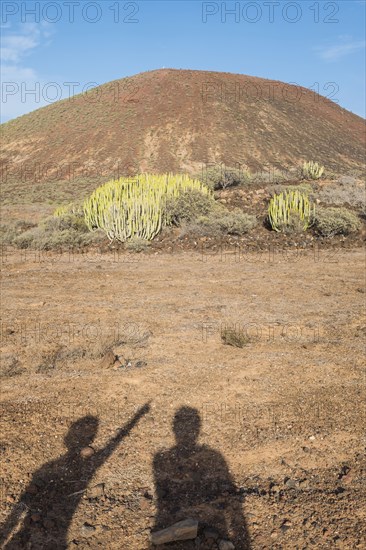 Shadows of people pointing at hill