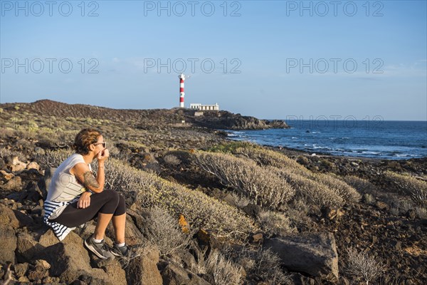 Caucasian woman sitting on rocks at ocean