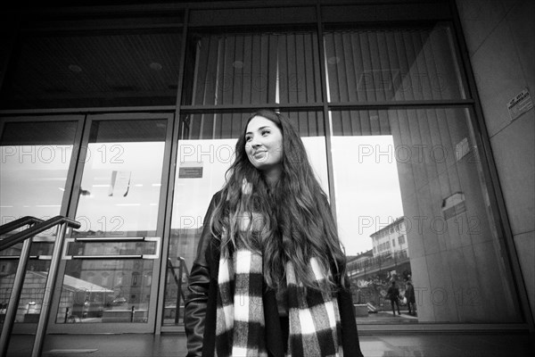 Smiling Caucasian woman standing near building