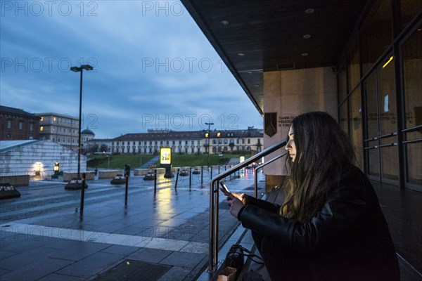 Caucasian woman sitting on staircase outdoors texting on cell phone