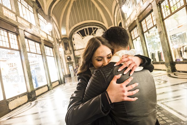 Caucasian couple hugging in lobby