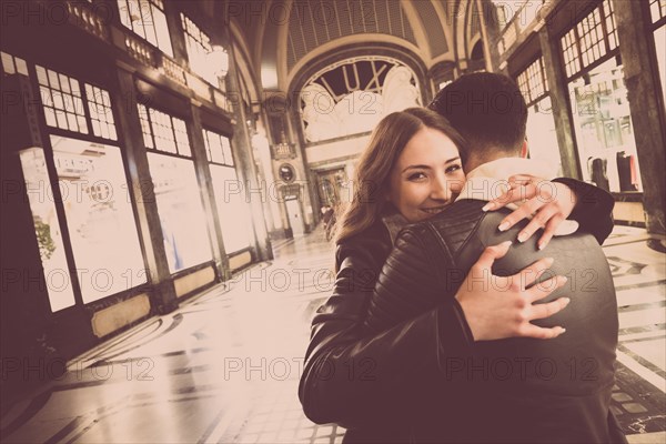 Smiling Caucasian couple hugging in lobby